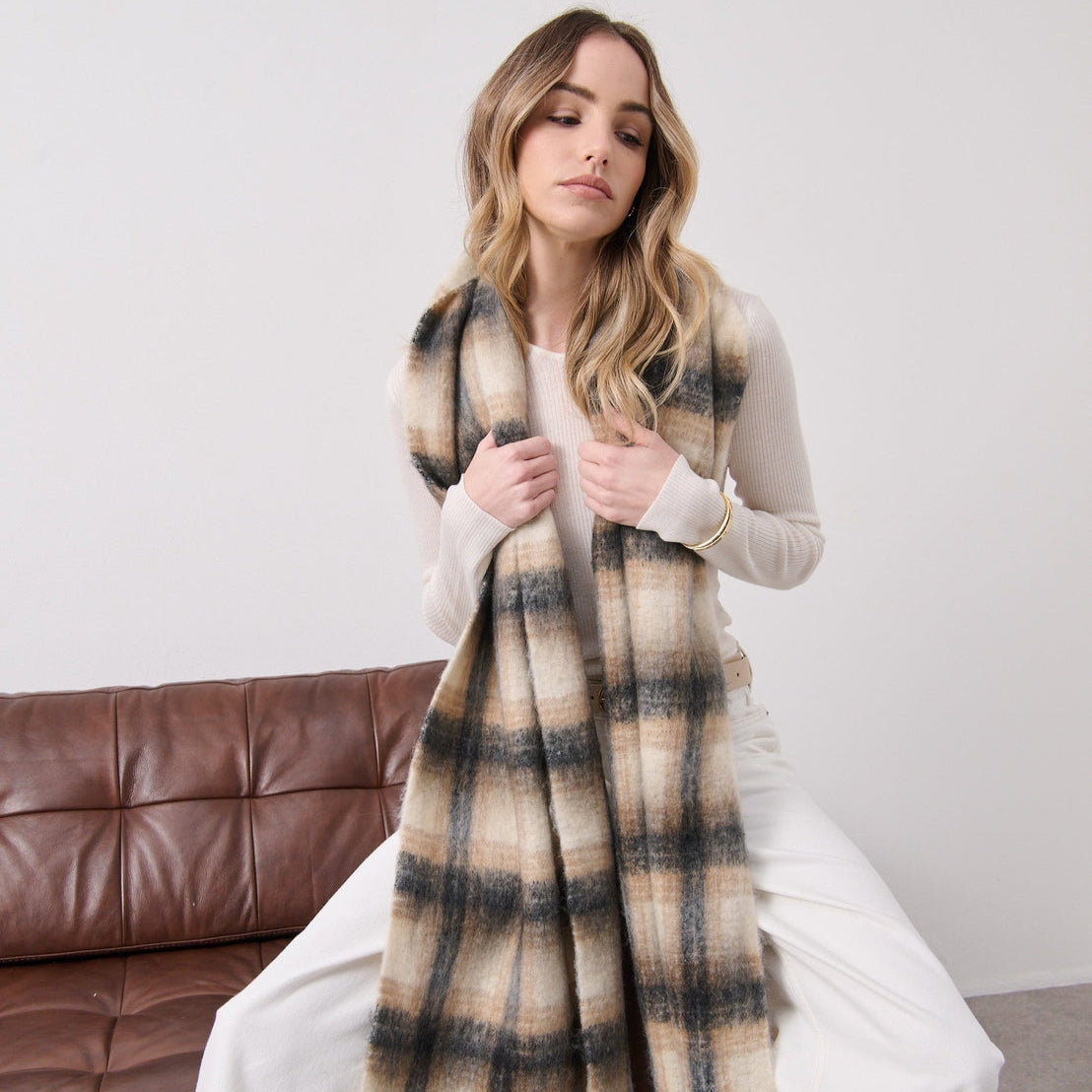 Woman sitting on a couch wearing a plaid scarf