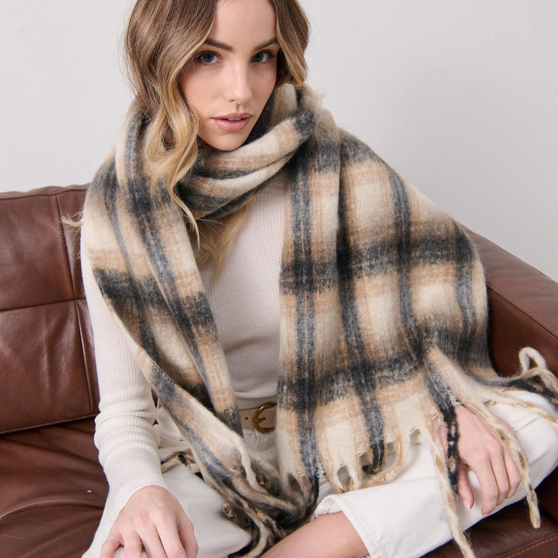 Woman wearing a plaid scarf sitting on a brown couch