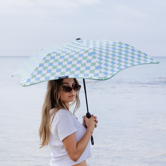 Woman holding a checkered umbrella on a beach