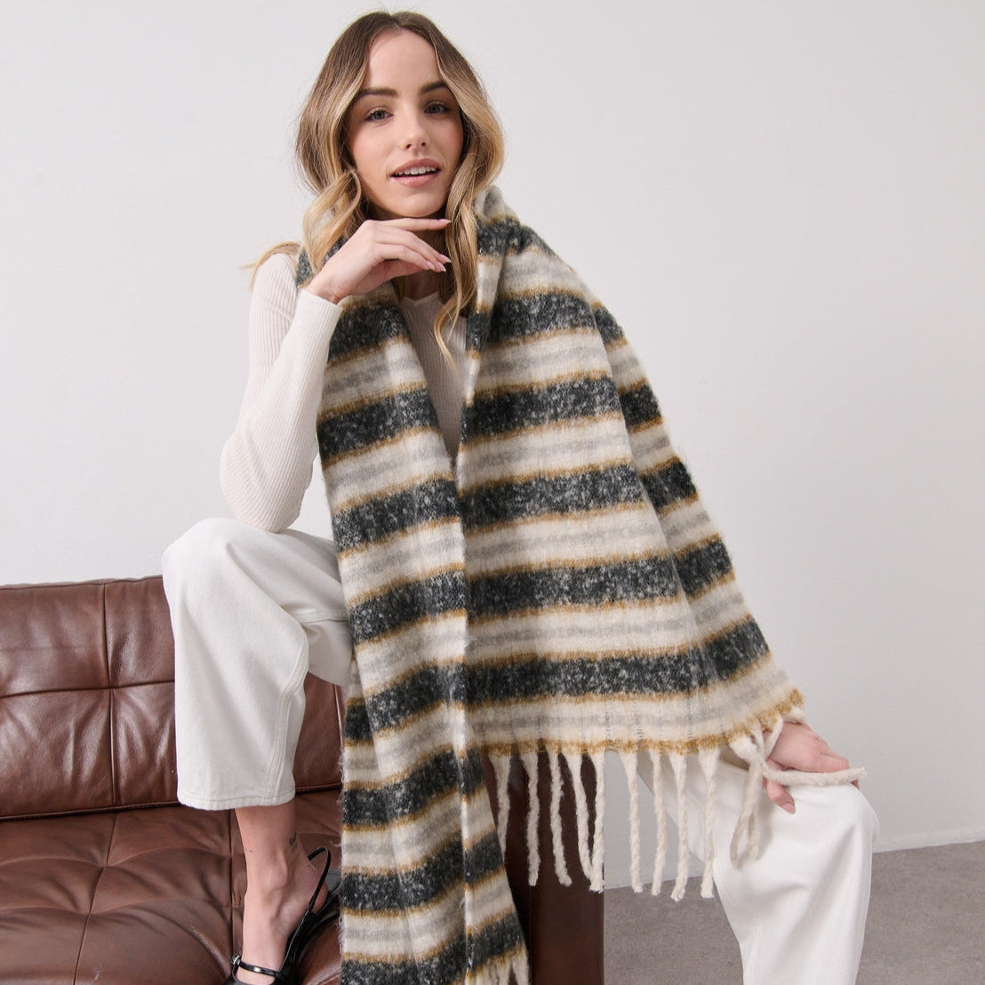 Woman wearing a striped scarf sitting on a brown couch 