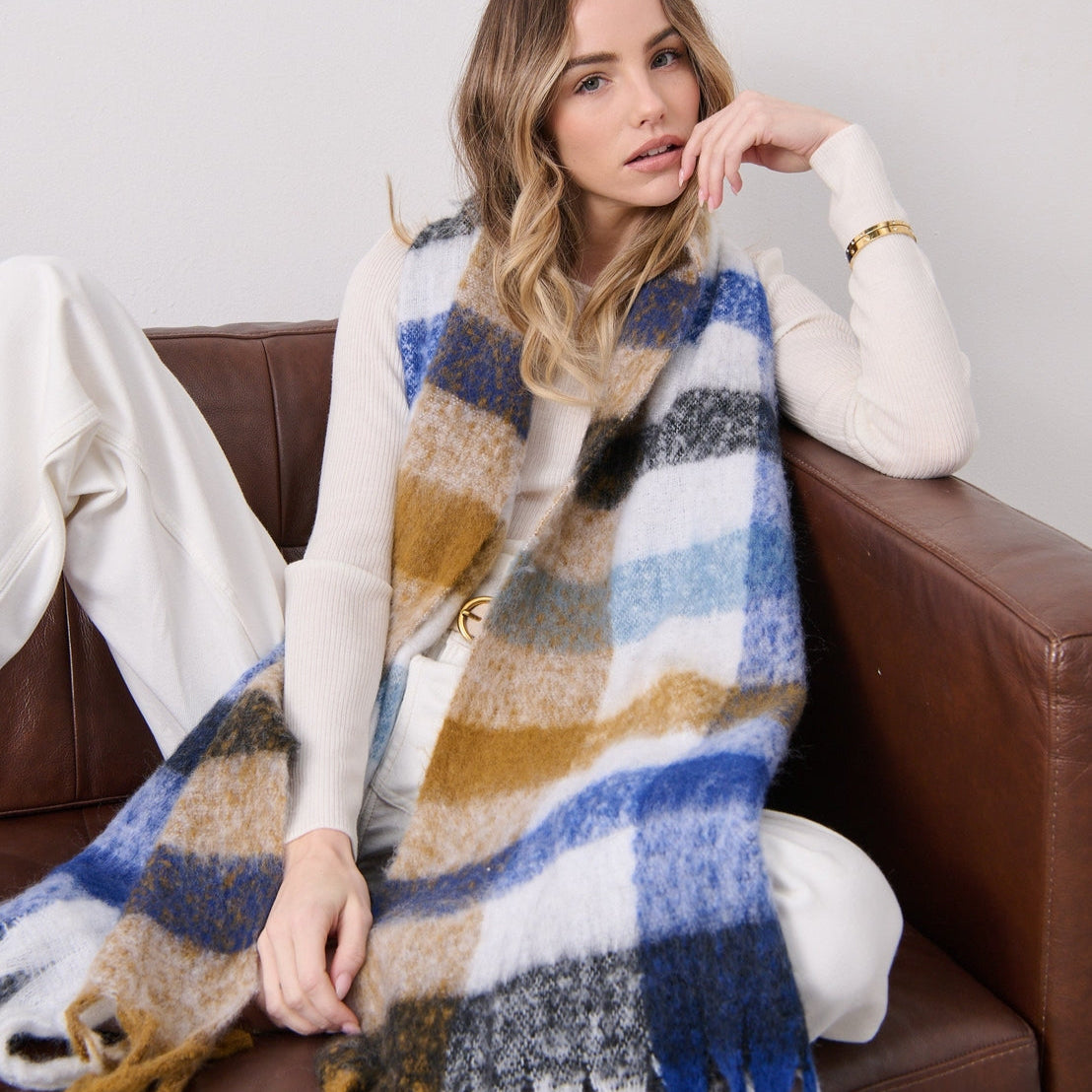 Woman sitting on a couch wearing a large plaid scarf