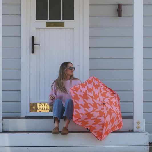 Woman sitting on a porch with a colorful umbrella